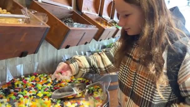 Meisje met verschillende snoepjes op de toonbank zijn gelegd alle kleuren van de regenboog zo veel als het speeksel stroomt van gelei beeldjes naar pasta en chocolade. — Stockvideo