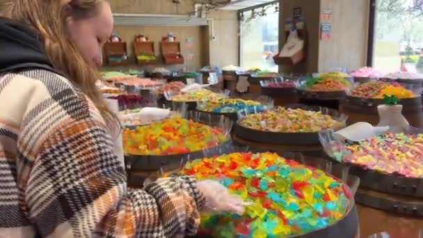 Fille avec différents bonbons sur le comptoir sont disposés toutes les couleurs de l'arc-en-ciel autant que la salive coule des figurines de gelée aux pâtes et au chocolat. — Video