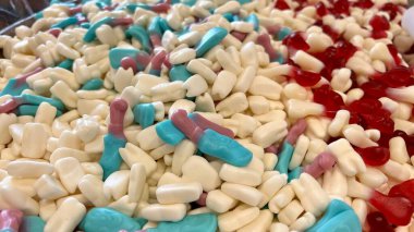 Tezgahtaki farklı tatlılar, gökkuşağının tüm renkleri, jöleli heykelcikten makarna ve çikolataya aktığı kadar serilmiştir..