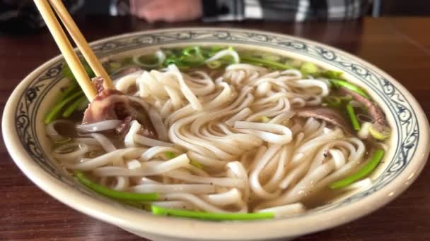 Vietnamese soup Fa Bo on a plate with beef and rice noodles is the unsurpassed taste of it eaten with chopsticks — Stock Video