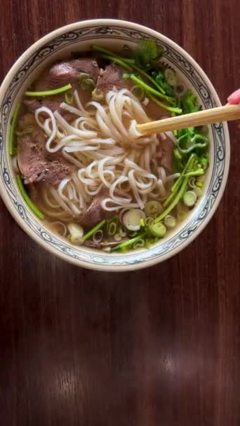 Вьетнамский суп Фа Бо на тарелке с говядиной и рисовой лапшой является непревзойденным вкусом его едят с палочками для еды — стоковое видео