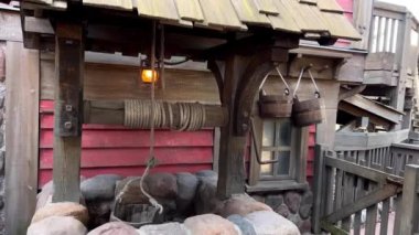 Taşla kaplı bir kuyu iki kova eski çatıyı asıyor ama hepsi çitin yanında biraz muhteşem duruyor.