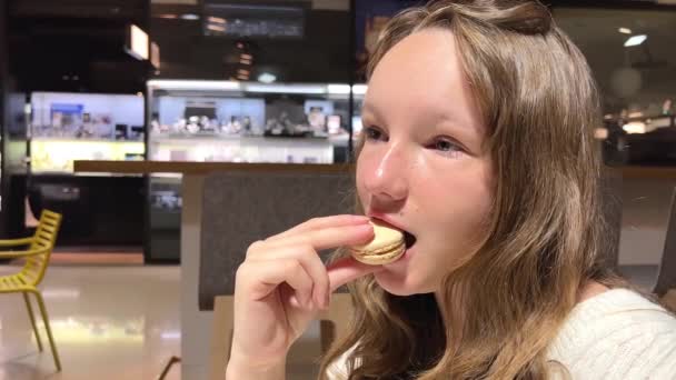 Tonåring flicka brunhårig kvinna med en mullvad ovanför läppen äter makaron närbild långsamt bita av den och blåser av glädje — Stockvideo