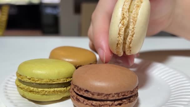 Macaroons on a plate close-up take a hand and turn one vanilla — Stock Video