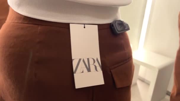 Barna nadrág és fehér póló a ruhaboltban Egy lány a próbafülkében méri a Zara ruhákat 06.04.22 Paris Franse Zara — Stock videók