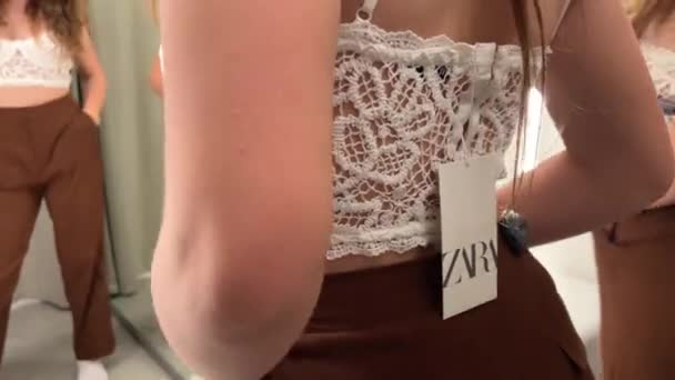 Biały ażurowy top i brązowe spodnie ubrane przez nastolatkę w sklepie Zara w przymierzalni pięknie ujęcie z bliska 06.04.22 Paris France Zara shop — Wideo stockowe