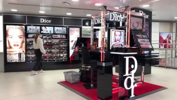 Chica adolescente en chaqueta blanca y pantalones negros pasea por la tienda de cosméticos mira el brillo labial 06.04.22 París Francia — Vídeo de stock