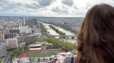 Eyfel kulesindeki bir kız Paris şehrine bakar. Görünür evler Seine Nehri ve şehir merkezi 06.04.22 Paris Fransa.