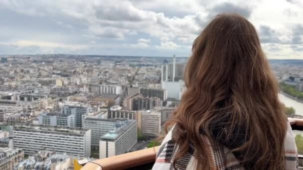 Una chica en una torre eiffel mira alrededor de la ciudad de París casas visibles el río Sena con barcos y el centro de la ciudad 06.04.22 París Francia — Vídeo de stock