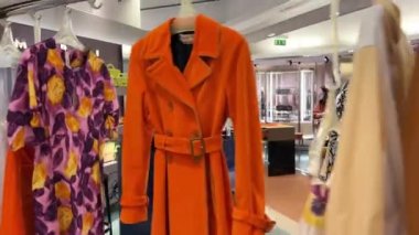 Satış ve tüketim kavramı: alışveriş merkezinde gezen renkli kese kağıtlarıyla alışveriş yapan kız. Etekli kadın bacakları moda butik askıları arasında yürüyor. Kağıt işleriyle uğraşan genç iş kadınının ayakları.