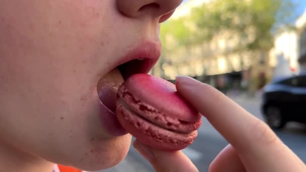 Dospívající dívka hnědovlasá žena s znamínkem nad rtem jí makarón zblízka ukousne a fouká s potěšením — Stock video