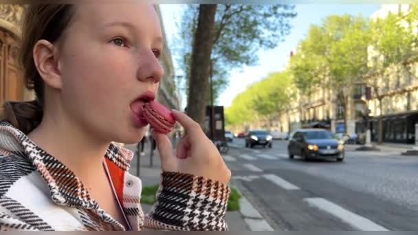 Adolescente femme aux cheveux bruns avec une taupe au-dessus de sa lèvre mange makaroon gros plan lentement mordre et souffle avec plaisir — Video