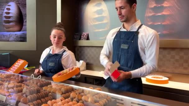 Leven in de banketbakkerij Makarunov Pierre Edme in blanke verkopers pogen kopers te behagen Veel makarons en een meisje in het wit kiest voor een smaak 06.04.22 Parijs Frankrijk — Stockvideo