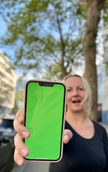 Tiener meisje met losse haar bruin haar bruin haar danst met telefoon vreugde op het scherm van kreupelheid groen scherm beige achtergrond — Stockfoto