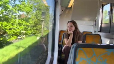 Genç kız kahverengi saçlı, kahverengi elbiseli, metro maskesini takmış ve maske taktığı bir video var. Trenle yürür. Telefonda yeşil ekran gösteriyor Dans ediyor ve gülümsüyor.