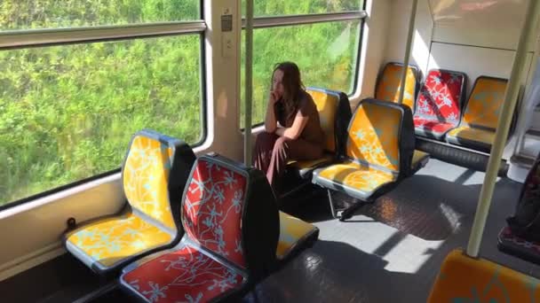 Κορίτσι ιππασία το τρένο δεν υπάρχει κανείς Είναι μόνη της είναι σε ένα καφέ κοστούμι όμορφη με ξανθά μαλλιά στο δρόμο, άνοιξη, δέντρα αναβοσβήνει από, αργή κίνηση βίντεο, σκέφτεται — Αρχείο Βίντεο
