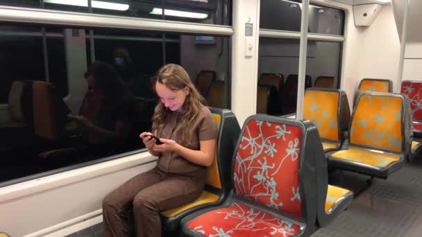 Nastolatka trzyma zielony ekran z kluczem chroma w rękach, tańczy, uśmiecha się, patrzy w kadr, pokazuje klasę i jest bardzo zadowolona, że jest sama w pociągu jeździ słonecznie po ulicy — Wideo stockowe