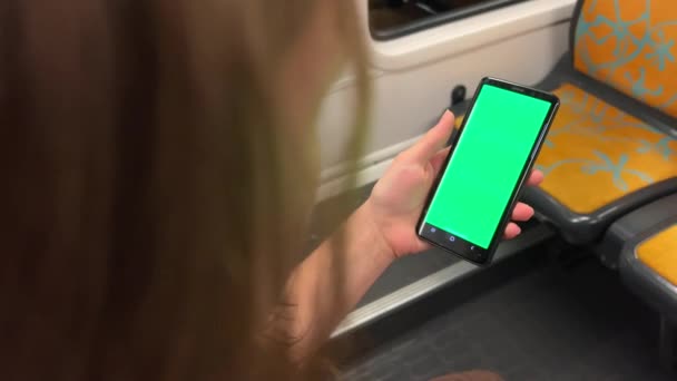 Una adolescente sostiene una pantalla verde con una llave de croma en las manos, baila, sonríe, mira dentro del marco, muestra clase y está muy contenta de estar sola en los paseos en tren soleada en la calle — Vídeos de Stock
