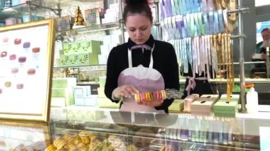 Güzel, Fransa 22.04.22 Laduree mağazasından ünlü Fransız makarnaları. Ahşap arka planda yeşil bir hediye kutusu. Hediyelik kutusunda çeşitli Laduree makarnaları var..