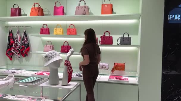 Beautiful teenager girl walks in a clothing store looking at handbags clothes hats and various other things — Vídeo de Stock