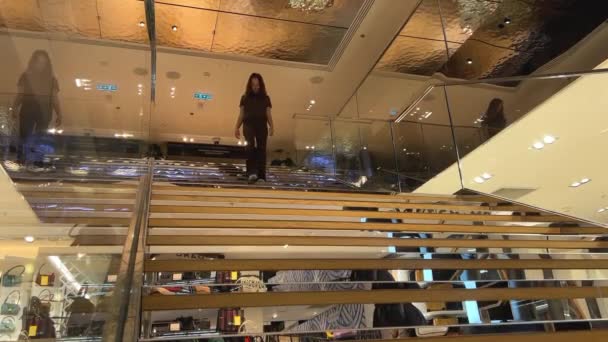 Beautiful teenager girl walks in a clothing store looking at handbags clothes hats and various other things — Vídeo de Stock