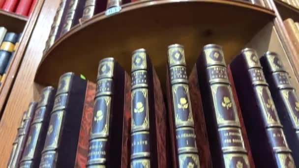 Verzamelbare boeken op de planken in de bibliotheekwinkel in een dikke chique ingebonden stand precies op rekken aan het plafond, boeken van Hugo Moliere en andere auteurs 26.04.22 Parijs Frankrijk — Stockvideo