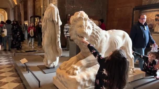 Beeldhouwkunst van de Leeuw en echte kleine meisjes spelen en steken hun vingers in hun mond en niet alleen 26.04.22 Parijs Frankrijk Louvre — Stockvideo