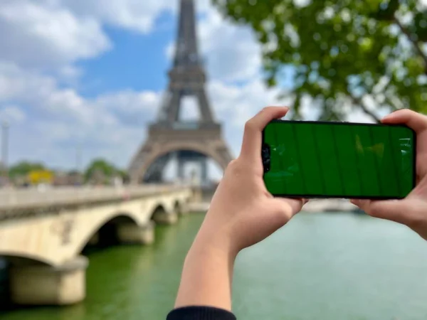 Phone with green Chromate screen on the background of the eiffel tower. in Paris using her cell phone in front of Eiffel Tower, seine bridge background, — стоковое фото