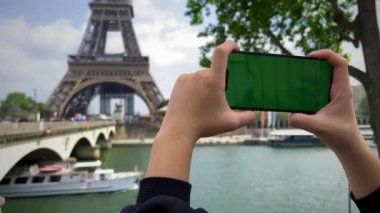 Eyfel Kulesi 'nin arka planında yeşil renkli ekran olan telefon. Paris 'te Eyfel Kulesi' nin önündeki cep telefonuyla, Seine Köprüsü arka planında., 