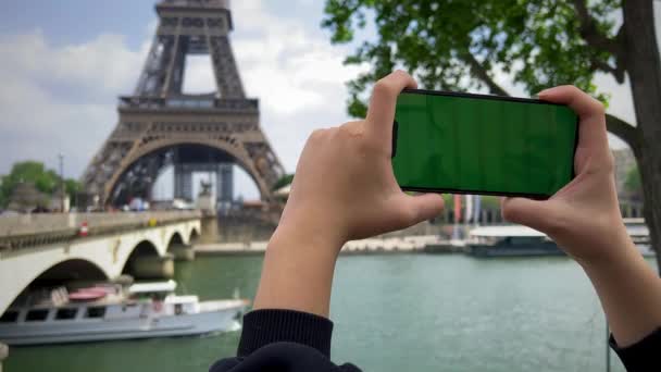 Teléfono con pantalla de cromato verde en el fondo de la torre eiffel. en París usando su teléfono celular frente a la Torre Eiffel, fondo del puente de cerco, — Vídeos de Stock