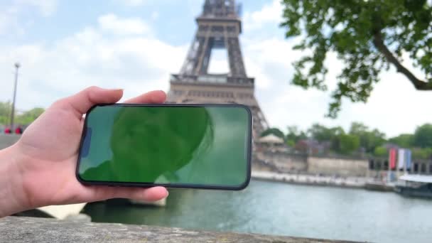 Telefon se zelenou chromovanou obrazovkou na pozadí Eiffelovy věže. v Paříži pomocí mobilu před Eiffelovou věží, zázemí mostu, — Stock video