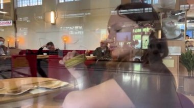 Genç bir kız büyük bir makarnayı zevkle ısırır, gerçekten sever, bir restoran reklamı ya da şeker reklamı olabilir.