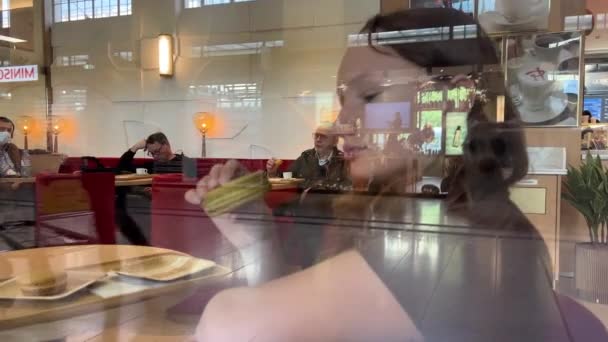 Ein Teenager-Mädchen beißt mit Vergnügen in eine große Pasta, sie mag sie wirklich, es kann eine Werbung für ein Restaurant oder Süßigkeiten sein — Stockvideo