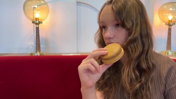 Egy tinédzser lány megharap egy nagy tésztát örömmel, nagyon szereti, lehet egy étterem hirdetése vagy édességek — Stock videók