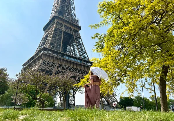 Una hermosa chica en un vestido largo se levanta contra el cielo azul y la Torre Eiffel en un restaurante. Ella mira en el marco hay un lugar para la agencia de viajes de publicidad — Foto de Stock