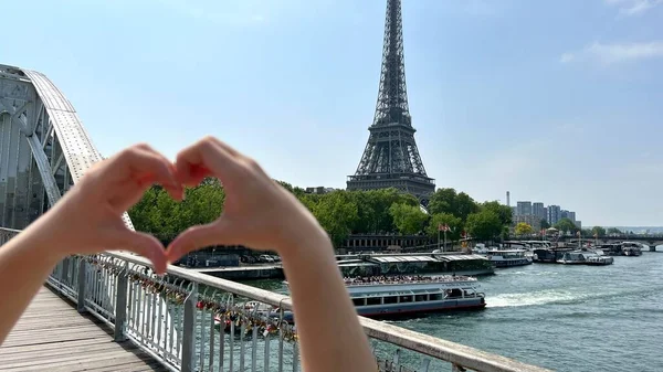 A man shows a heart with his hands connecting his fingers on the background of the Eiffel Tower — Zdjęcie stockowe