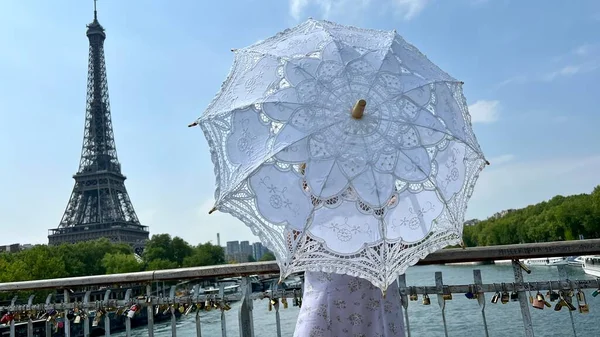 A girl with a white parasol stands against the backdrop of the Eiffel Tower with her back to us can be used for advertising for the Internet for travel agencies — Stok fotoğraf
