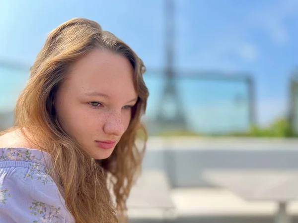 Tender face of a girl with freckles close-up she has blond hair and bright eyes She looks and can be used for any advertisem ent there is a place for text Eiffel Tower in the background — Stock Fotó