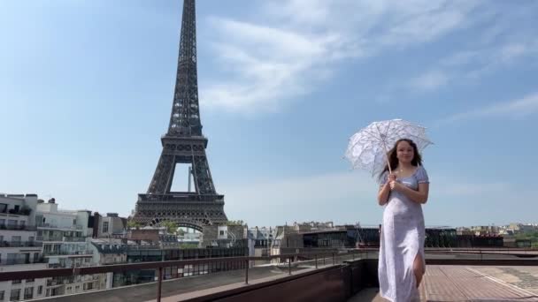 Дівчина, що ходить з парасолькою, ідеально підходить для будь-якої історії про Париж, струнка дівчина дивиться на Ейфелеву вежу, але все, що ми бачимо - це парасолька і блакитне небо. — стокове відео