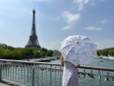 Paris 'le ilgili her hikaye için mükemmel bir zemin. İnce bir kız Eyfel Kulesi' ne bakıyor. Ama tek gördüğümüz bir güneş şemsiyesi ve mavi bir gökyüzü.