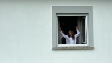 Genç bir kız beyaz perdeleri açar ve beyaz pencereden dışarı bakar. Videonun sağ tarafında, sol tarafta mesaj için çok yer vardır. Dışarı bakar ve gülümser.