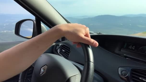 Ένας άντρας με γυαλιά ηλίου οδηγεί ένα αυτοκίνητο έχει ένα όμορφο ιταλικό πρόσωπο δείχνει την απόσταση και χαμογελά έξω από το παράθυρο του βουνού γκρεμό και τον ουρανό — Αρχείο Βίντεο