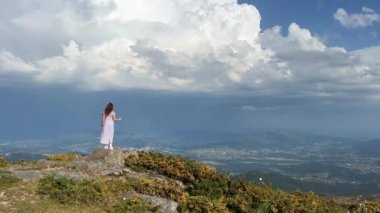 Bir kız yüksek bir dağda dans ediyor. Ellerini kaldırdı. Uzun saçları var. Her yerde mesaj, kredi ve reklam için bolca yer var.