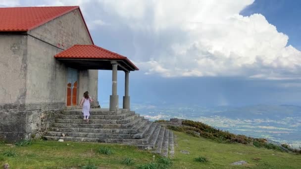 Une jeune fille monte les marches de l'église qui est située sur une haute montagne autour de l'espace il y a beaucoup d'espace pour la beauté sans fond de texte — Video