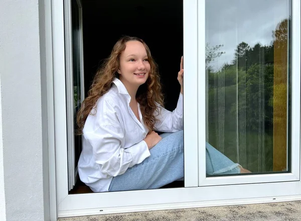 Онлайн кабинет сидящая дома на карантине девочка в белой блузке смотрит в окно — стоковое фото
