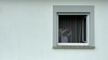 Genç bir kız beyaz perdeleri açar ve beyaz pencereden dışarı bakar. Videonun sağ tarafında, sol tarafta mesaj için çok yer vardır. Dışarı bakar ve gülümser.