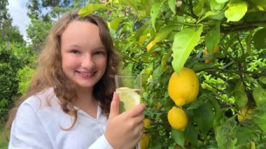 Beyaz tişörtlü bir kız limonlu bir limon ağacının arka planında biatlon oynuyor. Yüksek kalite 4k görüntü