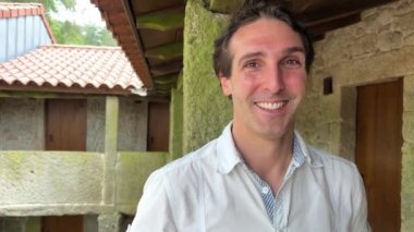 Avrupa görünümlü yakışıklı bir adam, dağların arka planında ve mavi gökyüzünde duruyor. Beyaz bir gömlekle çerçeveye bakıyor ve gülümsüyor. Mesajlaşmak için bir yer var. Yüksek kalite 4k görüntü