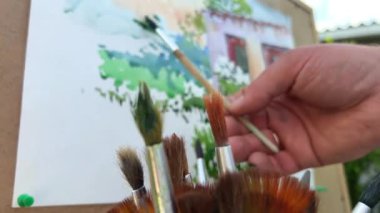 Ressamın şu anda çizmekte olduğu tablonun arka planına karşı çok farklı fırça uçları var. Ressamın gerçekten resim yaptığı bir fotoğraf var. Yüksek kalite fotoğraf