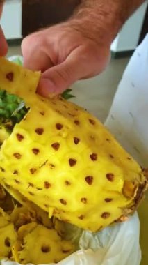 Erkek eli ananasları sarı bir meyve suyu kasesine kesiyor. Yüksek kaliteli görüntüler